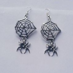 This listing is for one pair of Hanging Spider Web Dangle Earrings. Web and Spider charms measure approximately 44mm long and are attached to lead/nickel free silver toned hooks. Earrings come in a colorful organza pouch. Gift box may be purchased if sending as a gift. May also include a note to recipient if desired (no extra charge). Themed Dangle Pierced Earrings, Hypoallergenic Drop Earrings For Halloween, Gothic Plug Earrings For Halloween Gift, Gothic Halloween Plug Earrings As A Gift, Silver Witchy Earrings, Silver Ear Wire Earrings For Halloween, Dangle Earrings As Halloween Gift, Handmade Metal Earrings For Halloween, Dangle Earrings For Halloween Gift