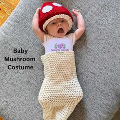 a baby in a mushroom costume is laying on the floor with his hands behind his head