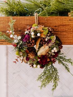 a christmas wreath hanging from the ceiling with pine cones and other holiday decorations on it