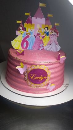 a pink birthday cake with princess figures on it's top and the number six