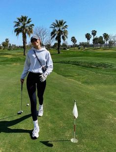 a woman walking across a green covered golf course