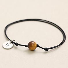 This handmade bracelet made of black textile features a tiger eye bead, which represents strength and energy. The simple but powerful stone is securely fastened with two knots and makes the bracelet a special companion in everyday life. Tiger's eye is known for its protective properties and strengthens inner strength and self-confidence. The bracelet is individually adjustable in length and is easy to put on, making it both a stylish accessory and an ideal gift for your loved one. This bracelet Energy Bracelets, Tiger Eye Beads, Tiger's Eye, Nature Bracelets, Handmade Bracelet, Inner Strength, Braided Bracelets, Stainless Steel Jewelry, Adjustable Bracelet