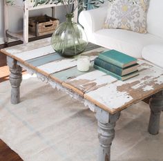 a coffee table with flowers in a vase on top of it and books on the bottom