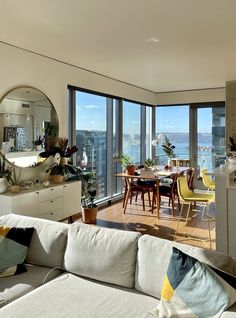 a living room filled with furniture and large windows overlooking the cityscape in the distance