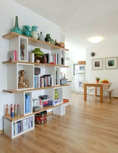 a living room filled with lots of furniture and bookshelves on top of wooden shelves