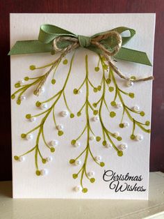 a christmas card with green and white berries on it, tied up to a bow