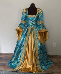 This striking gown is made from a vibrant turquoise blue, designer damask with a ornate gold pattern woven throughout.  The bodice features a deep, square neckline trimmed with gold braid to accentuate your decoletage. The gathered overskirt is firmly attached to the bodice, and is also trimmed with a stunning wide braid down the skirt fronts for a lovely elegant line.   The dramatic great sleeves are trimmed with the wide gold braid at the elbow, and the wide bell sleeves can be turned back to reveal the gorgeous gold lining.  The sleeves can be made attached or detachable. Closes at the back through brass grommets which allows for a more adjustable fit, and backed with a modesty panel. This bodice is boned along the front/side seams and at the grommet back closure. The gold underskirt is Blue Baroque Dress With Historical Design, Blue Baroque Dresses For Fancy Dress Events, Blue Baroque Costume Dress, Blue Rococo Dresses For Costume Party, Blue Historical Dress For Costume Party, Blue Historical Costume Party Dress, Blue Historical Design Dress For Costume Party, Blue Historical Wedding Dress, Blue Wedding Dress With Historical Design