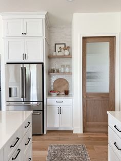 a kitchen with white cabinets and wood floors is seen in this image from the front door