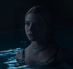 a woman in the water wearing a choker and looking off into the distance with her eyes closed