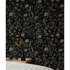 a black floral wallpaper with flowers and leaves in the background, on a bed