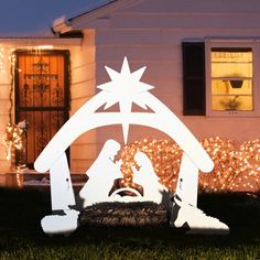 a nativity scene in front of a house with christmas lights