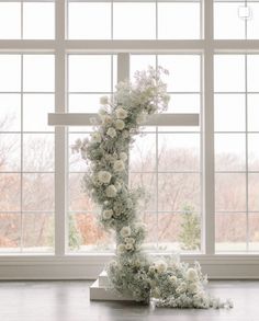 a cross made out of flowers sitting on top of a table next to a window