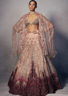 Rose pink to maroon ombre shimmer tulle lehenga heavily encrusted with micro Japanese cutdaana, sequins and crystal stones. Paired with embellished tulle blouse and shimmer tulle embroidered cape dupatta. Accentuated with feather and crystal details. Ombre Lehenga, Tulle Lehenga, Pink Bridal Lehenga, Tulle Blouse, Embroidered Cape, Wedding Lehenga Designs, Dress Idea, Saree Designs Party Wear, Vogue Dress