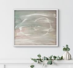 an abstract painting hangs on the wall next to a vase with eucalyptus leaves in it