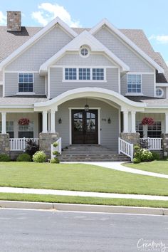 a large gray house with white trim on the front door and windows in the middle