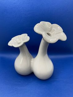 two white vases sitting side by side on a blue background