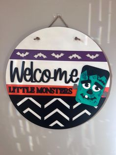 a sign that says welcome little monsters hanging on the wall in front of a door