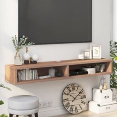 a living room with a large flat screen tv mounted on the wall and shelves below it