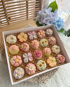 there is a box of decorated cookies on the table next to a vase with flowers