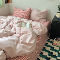 an unmade bed with pink sheets and checkered blankets on it in a bedroom