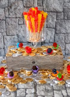 a wooden box filled with gummy bears next to a pile of gold coins and candy