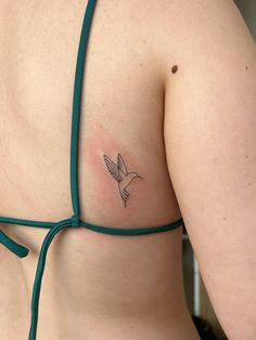 a woman with a small tattoo on her back shoulder and chest, wearing a green bra