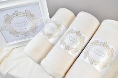 three white blankets with gold trim are sitting next to a framed photo and the words, love is in the air