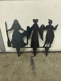 three metal silhouettes of witches on a wall