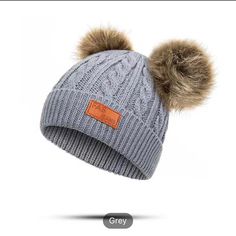 a gray hat with two brown pompoms on it and the word grey written in orange