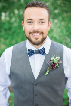 a man wearing a gray vest and blue bow tie