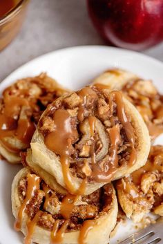 three cinnamon rolls on a white plate with caramel sauce drizzled over them