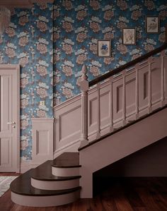 the stairs in this house are made of wood and have floral wallpaper on them