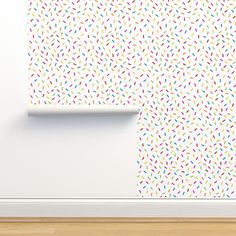 a white wall with colorful sprinkles on it next to a wooden floor