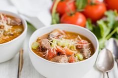 two white bowls filled with soup and vegetables