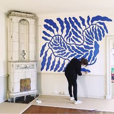 a man is painting on the wall in his living room with blue and white paint