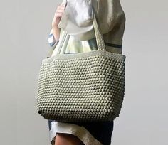 a woman is carrying a crocheted bag on her head with the word pattern written below it