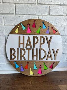 a happy birthday sign is shown on a wooden plaque that says happy birthday with colorful party hats