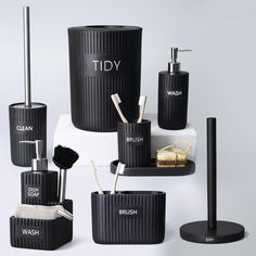 black bathroom accessories including soap dispenser, toothbrush holder and brush