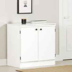 a white cabinet sitting in the corner of a room next to a door and rug