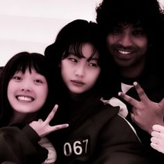 three young people posing for the camera with their fingers in the shape of two peace signs