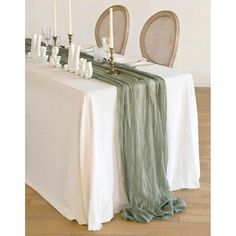 the table is set with two chairs and a white table cloth on it, along with candles