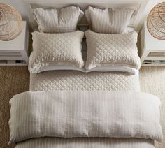 the bed is made up with white linens and beige pillows, along with wicker baskets on the wall