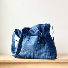 a blue jean purse sitting on top of a wooden table next to a white wall