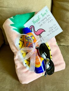 a beach towel, sunglasses, and sunscreen on a couch with a thank you sign