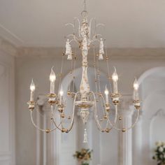 a chandelier hanging from the ceiling in a room with white walls and columns