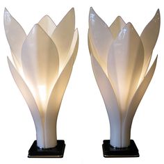 two white vases sitting on top of black bases