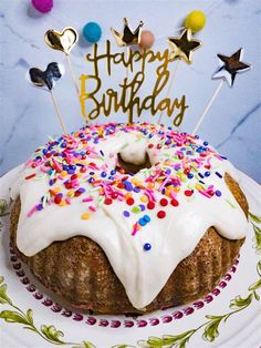 a birthday cake with white frosting and sprinkles on a decorative plate