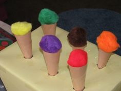 four ice cream cones with different colored toppings on top of each cone, sitting on a cutting board