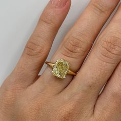 a woman's hand with a yellow diamond ring on it