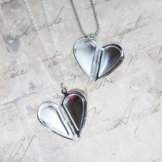 "A pair of silver heart lockets that opens to look like a whole heart and closes to look like half of a heart. The 2 matching necklaces makes up a complete heart! Place your favorite photos or print out meaningful words inside locket. This set of 2 necklaces come in a gift bag ready for gift giving. * Add a birthstone or initial charm from our add-on section to personalize necklace! ♥ Silver-plated brass heart locket measures approx. 16 x 25mm ♥ 18\" Sterling silver plated chain (female) ♥ 24\" Silver Double Heart Locket Necklace For Keepsake, Silver Open Heart Locket Necklace Nickel Free, Nickel-free Silver Open Heart Locket Necklace, Silver Double Heart Locket Necklace With Heart Charm, Silver Open Heart Locket Necklace With Heart Charm, Matching Necklaces For Couples, Couples Necklace, Heart Place, Photo Locket Necklace